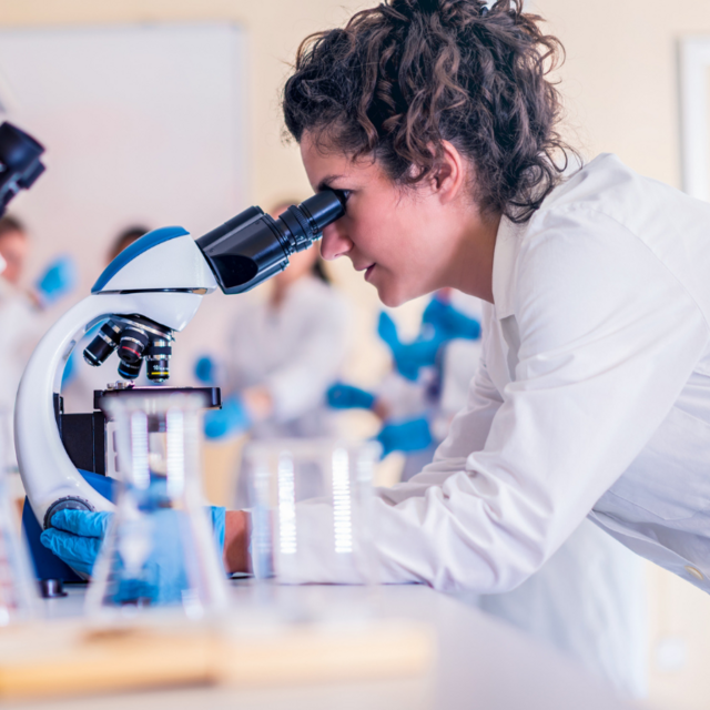 Female doctor looking through microscope